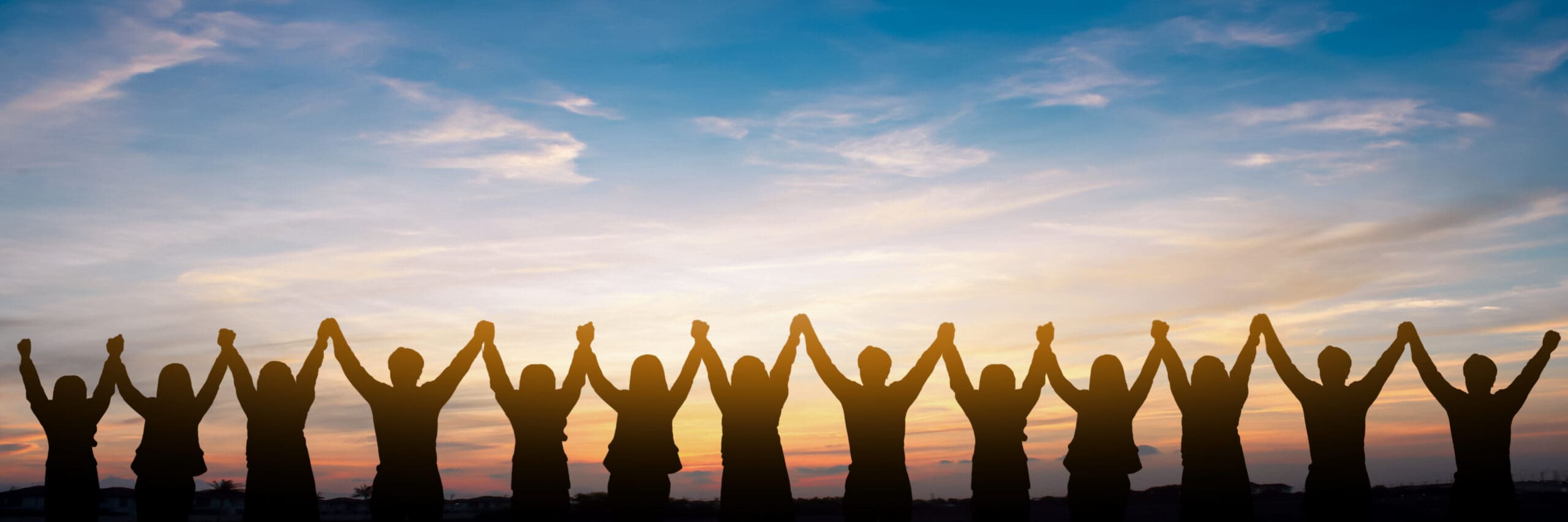 Silhouette of group of happy businesspeople with hands high over heads